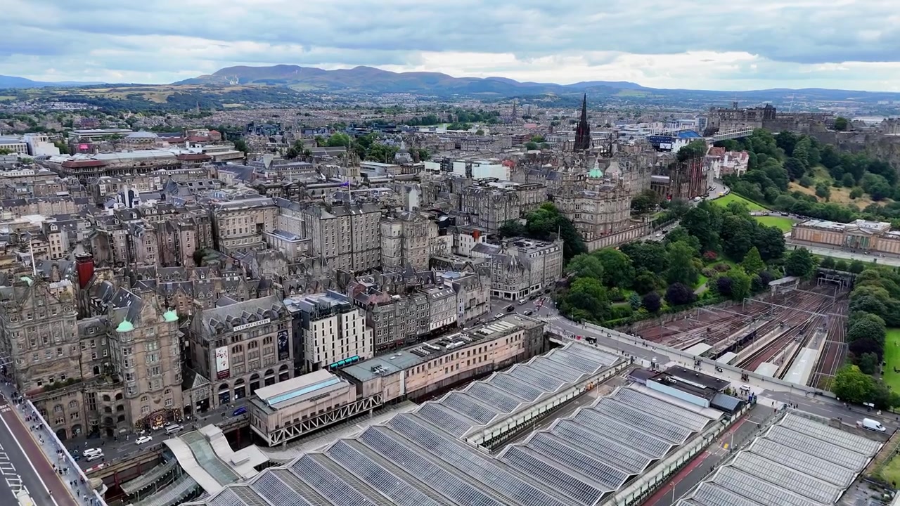 Sobrevoo aéreo da estação ferroviária Edinburgh Waverley em meio à arquitetura histórica. Escócia.