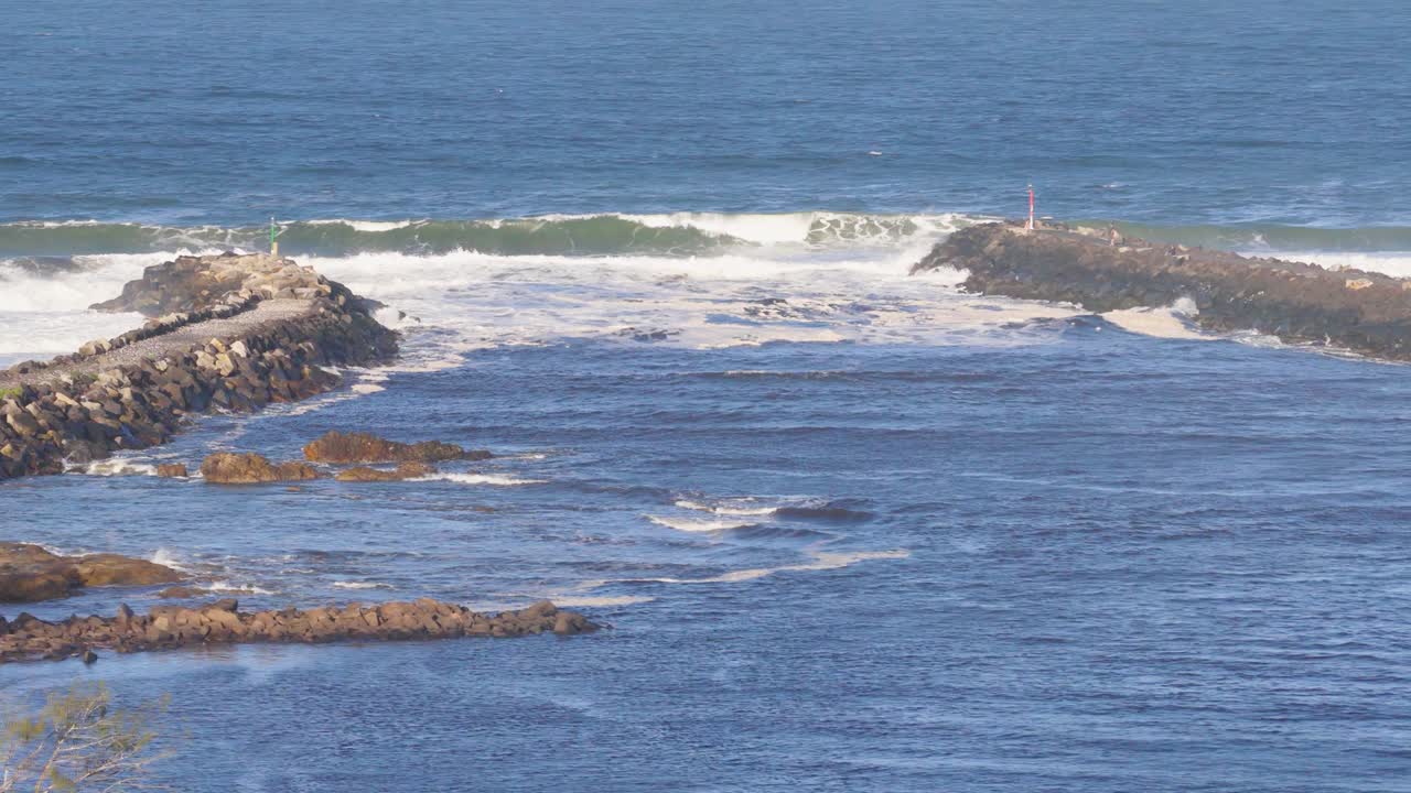 Drone footage captures the serene coastal landscape of Brunswick Heads with waves crashing against rocky outcrops