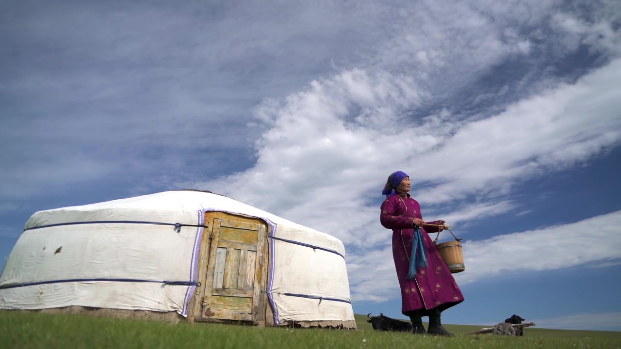 Mongolian Woman in Traditional Clothing Standing Outside Her Yurt