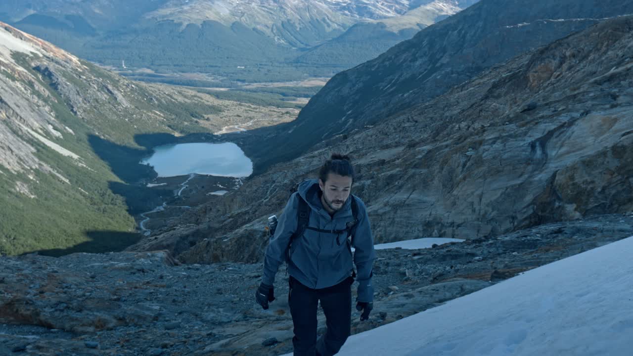 fotógrafo caminando en el glaciar ojo del albino en ushuaia, argentina con la laguna esmeralda en el fondo