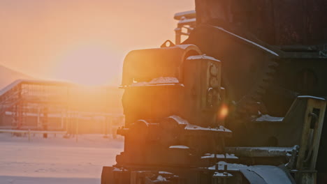 industrial machinery in a snowy landscape at sunrise/sunset