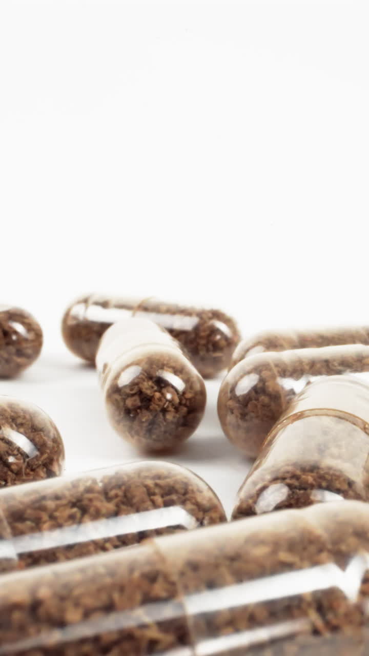 cápsulas transparentes dispersas con contenido herbal sobre fondo blanco