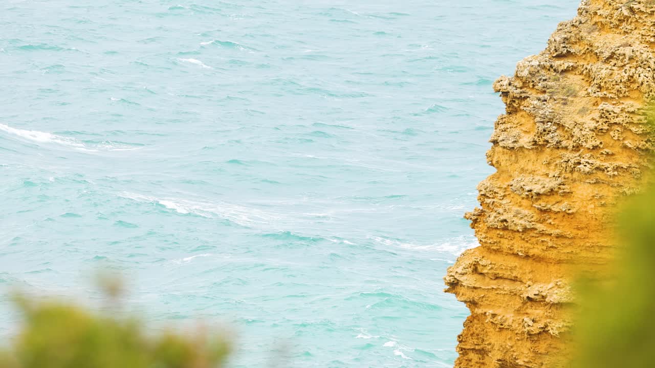 A serene view of a rugged cliff against the backdrop of the ocean, captured in natural daylight