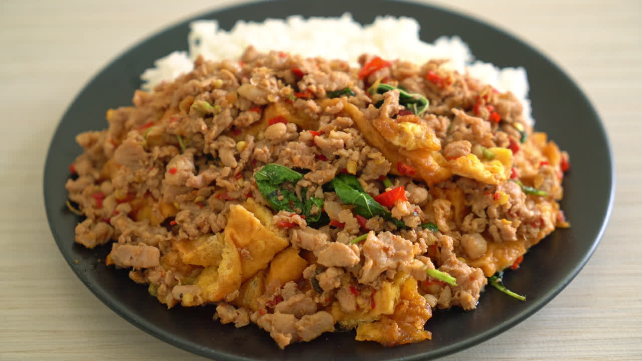 cerdo picado salteado con albahaca y huevo cubierto con arroz - estilo de comida asiática