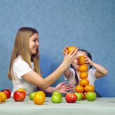 . happy little girl with fruits. little girl playing with fruits sitting at the table