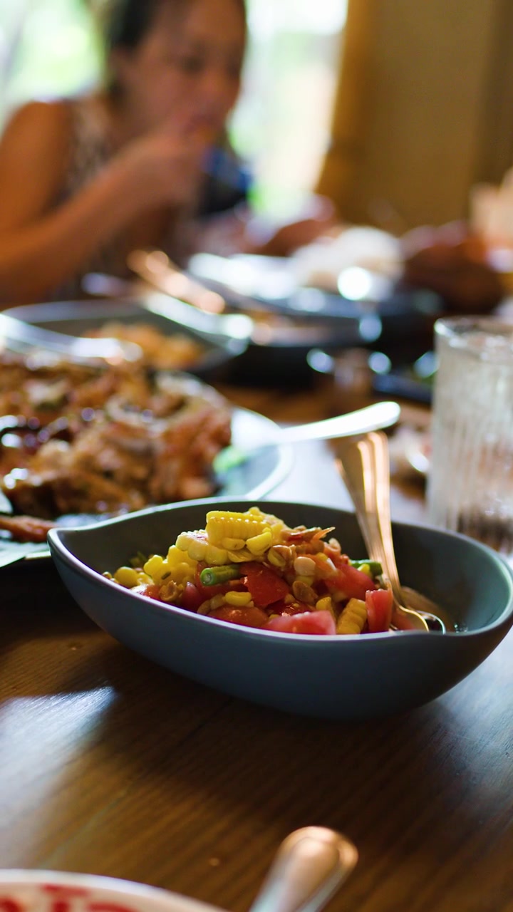 Close-up of Thai corn salad on table, family eating together, natural daylight, shallow focus