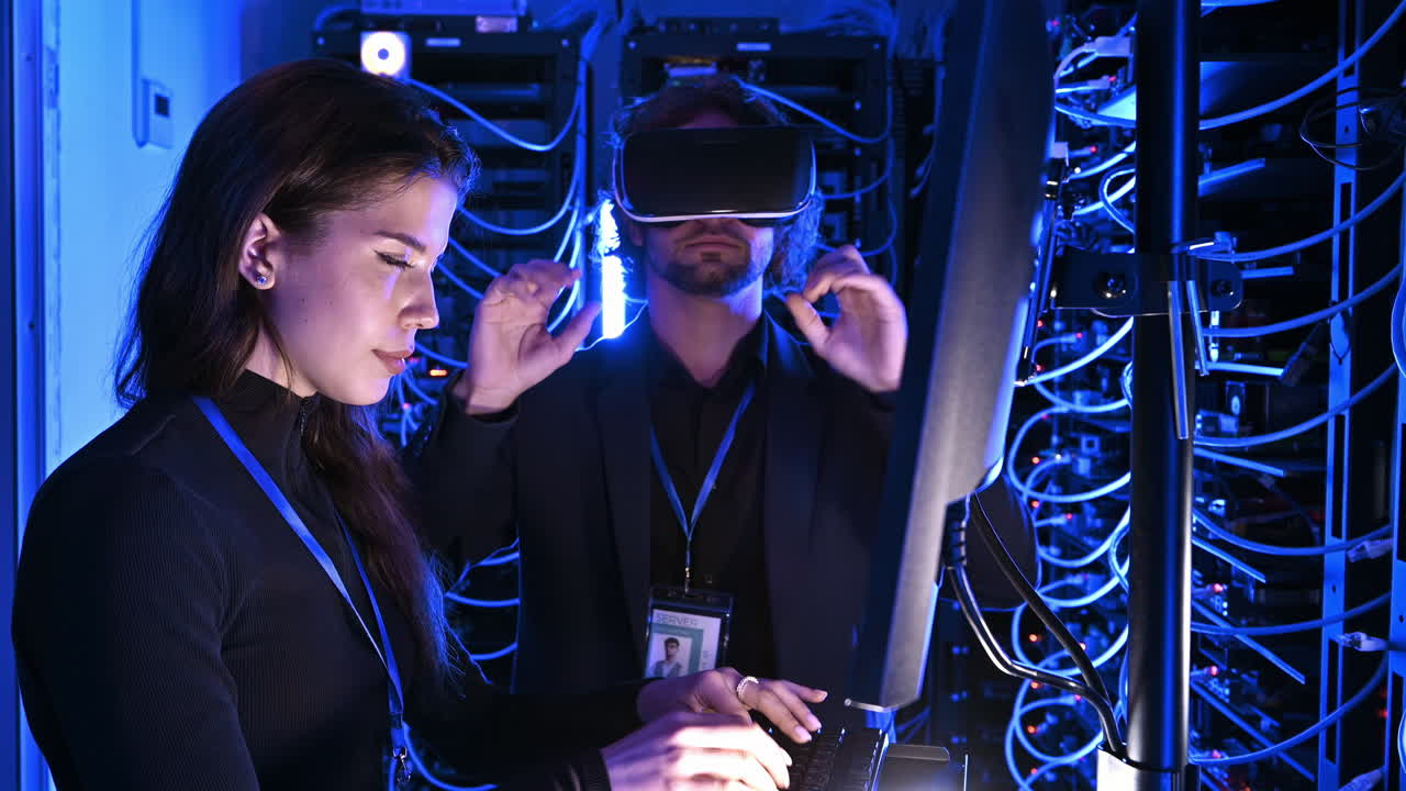 Woman programming in a server room while a man is using a Virtual Reality headset