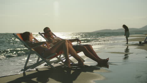 couple relaxing on beach at sunset