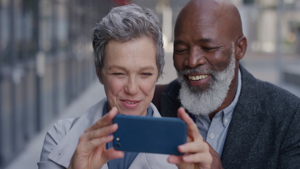 portrait happy senior multi ethnic couple using smartphone taking selfie photos posing enjoying making faces having fun together in city slow motion