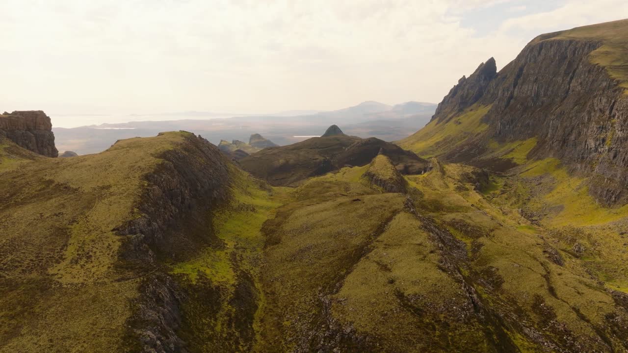Aerial drone footage of the dramatic mountain landscapes on the Isle of Skye, Scotland. Sweeping panoramic views of majestic peaks, green valleys, and wild nature. Quiraing walk