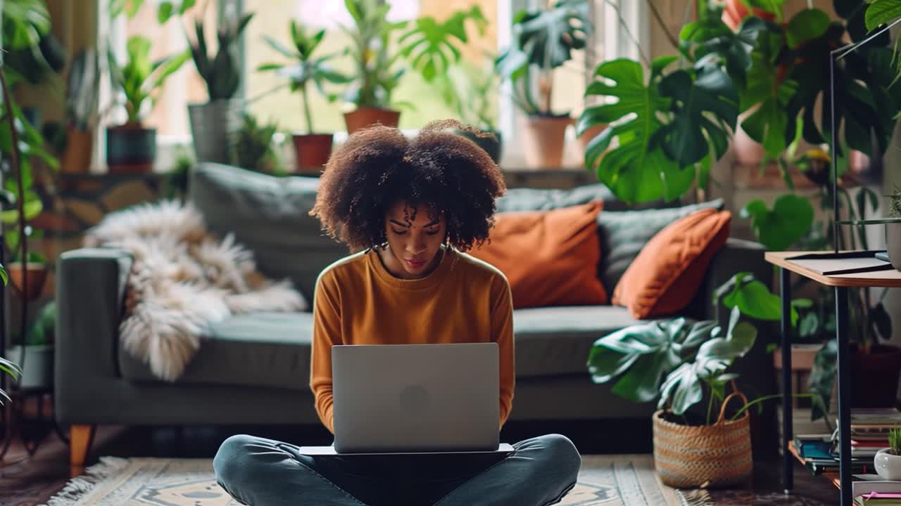 Woman working on laptop at home surrounded by plants