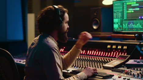 audio expert operating motorized faders and mixing console in control room