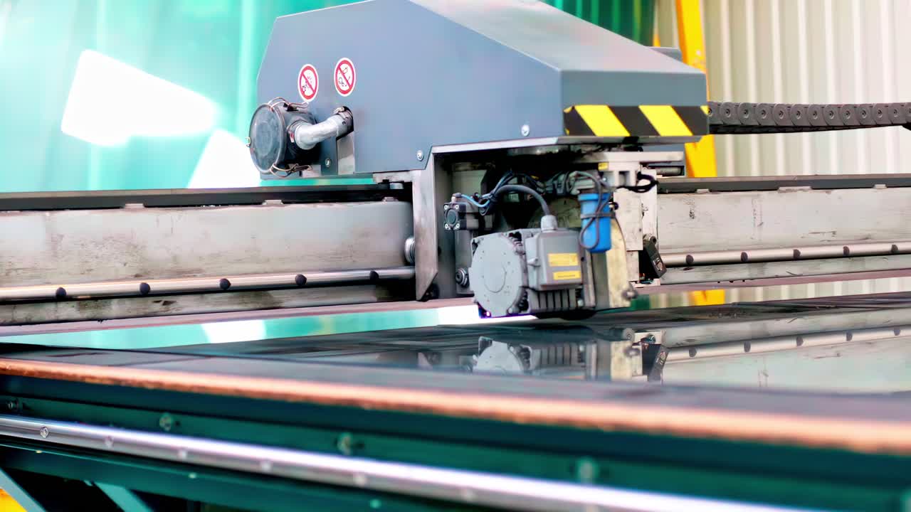 Industrial glass processing machine operating on reflective surface in factory setting