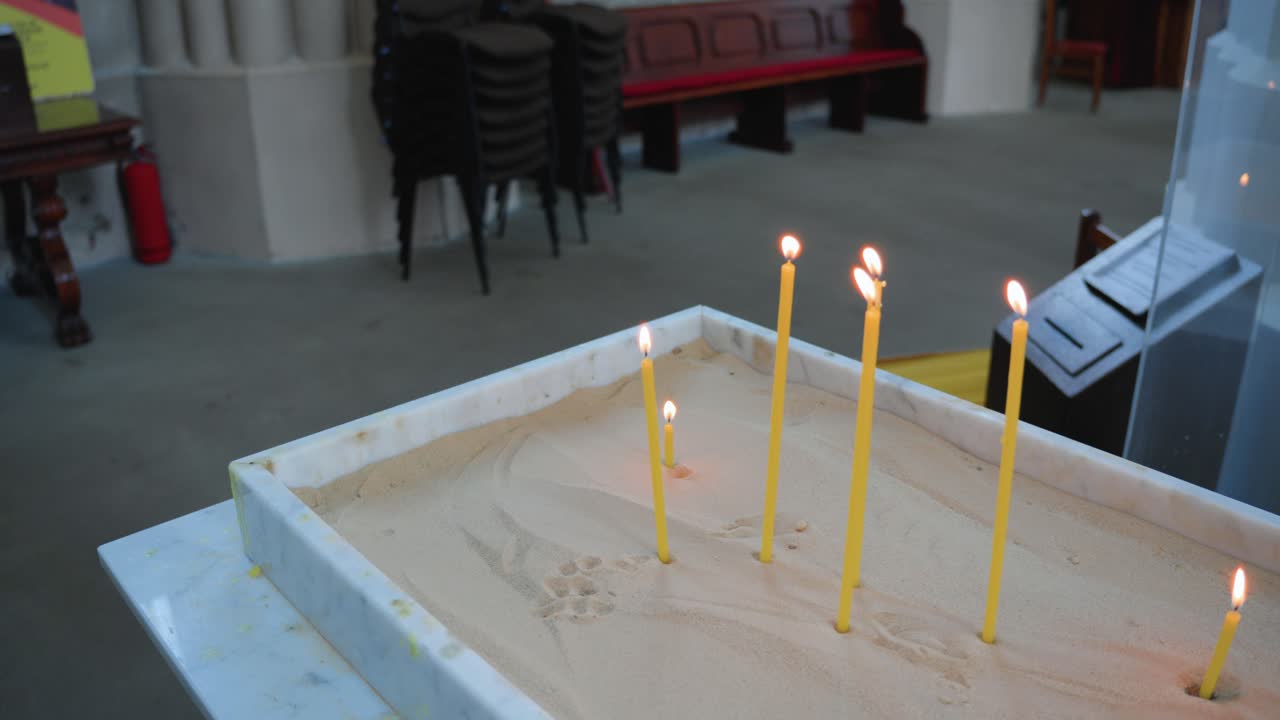 disparo de cerca de las velas de oración encendidas para los muertos en una caja de arena en una iglesia católica