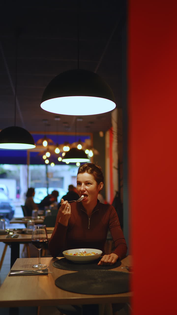 Mulher Desfrutando de uma Refeição e Vinho Tinto em um Restaurante