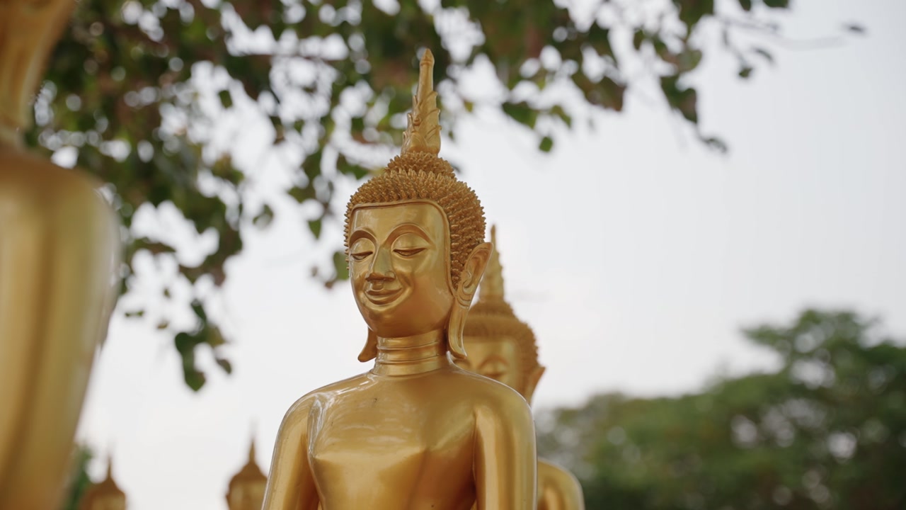 A serene golden Buddha statue in an outdoor setting at the Ancient City