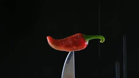 검은색 배경 의 칼 끝 에 은 칠리 고추 에 물 이 흘러 내리는 것 - 장면 뒤 에 있는 음식 광고