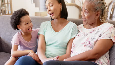 Sitting on couch, three generations of african american women talking and smiling together
