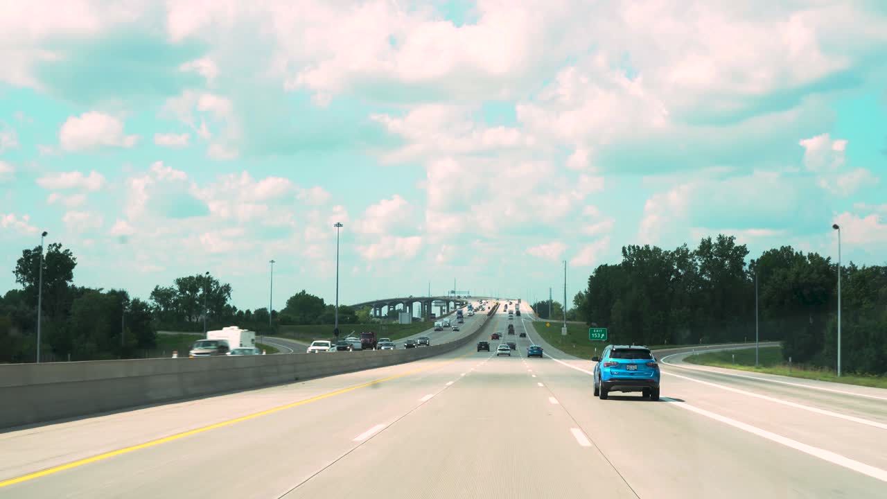 A highway in Michigan is shown in stunning color while approaching an impressive bridge structure in the distance