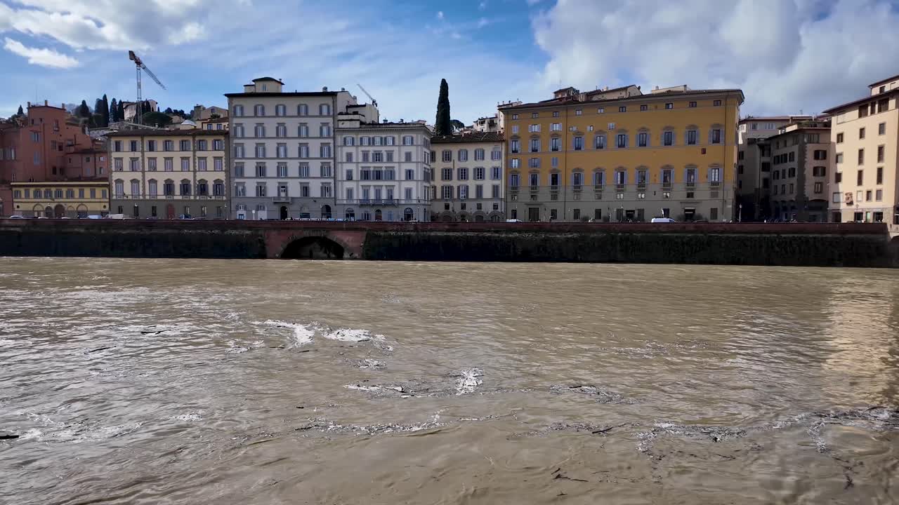 Toma estática a orillas del río Arno en Florencia, Toscana, Italia. La corriente del río fluye suavemente bajo un cielo soleado por la mañana, destacando uno de los paisajes más emblemáticos de la ciudad.