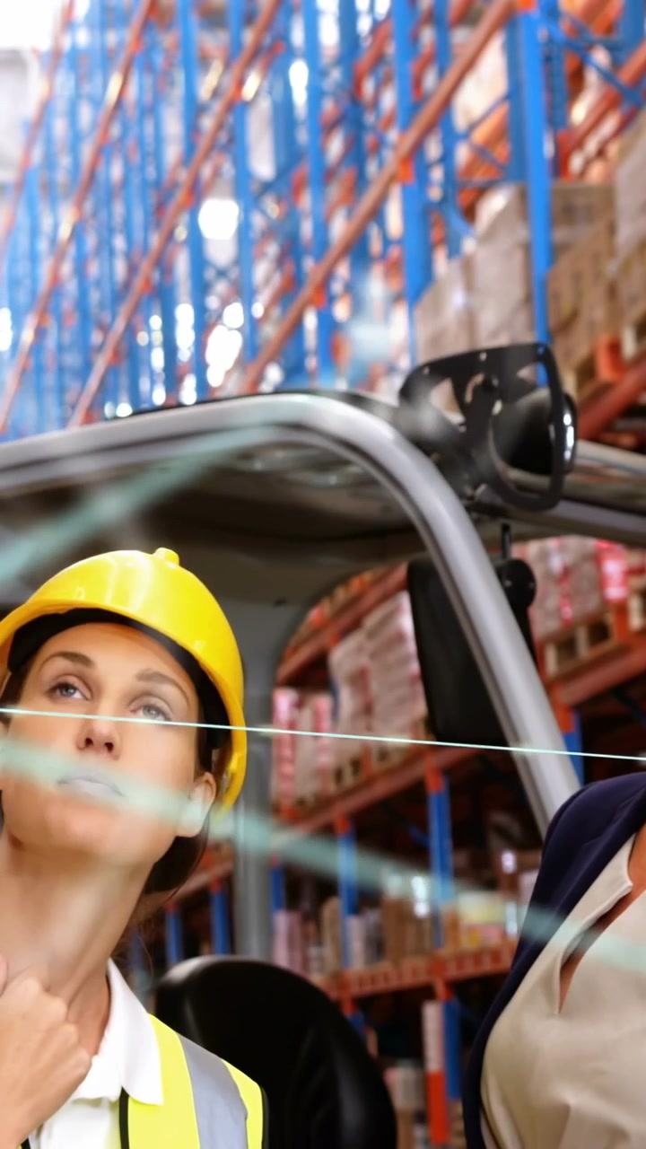Video verticale: Operatore che segue un manager che indica in un magazzino, esaminando la logistica con icone di realtà aumentata.