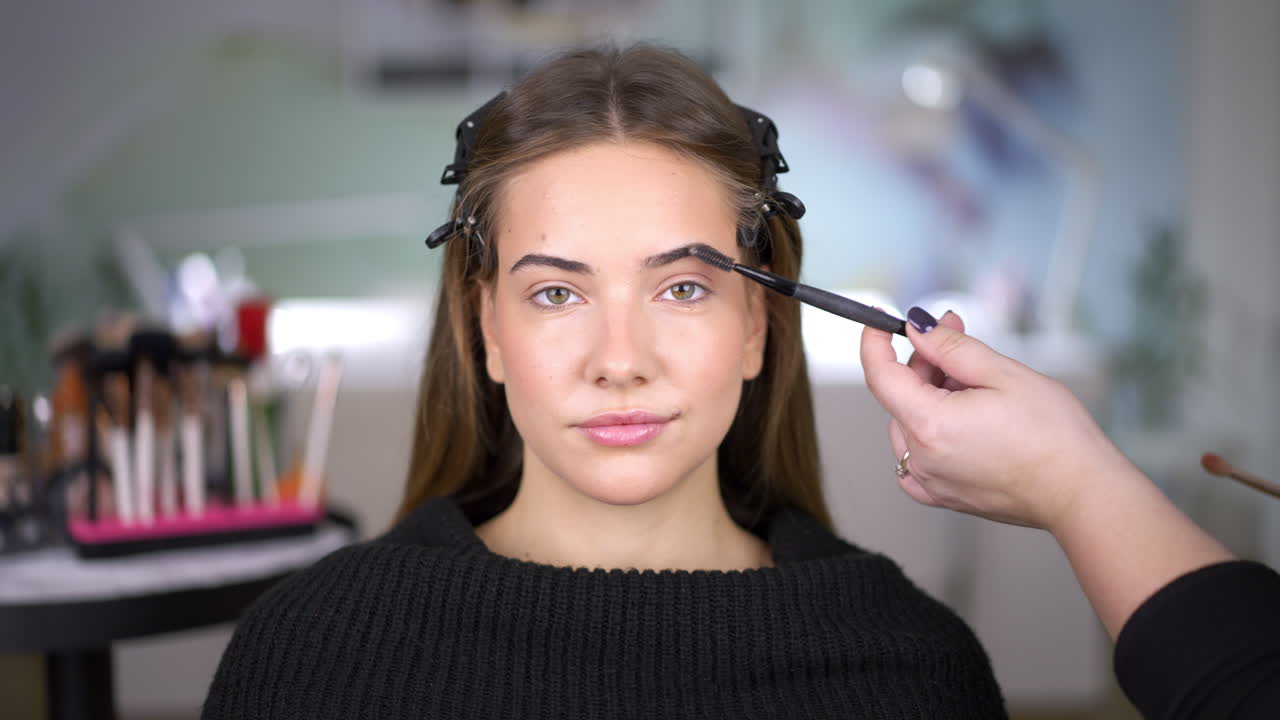 Close-up of a woman getting her eyebrows brushed during a makeup session