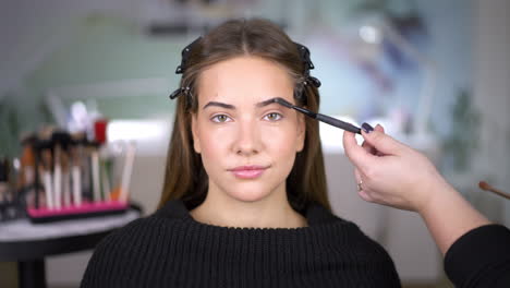 close-up of a woman getting her eyebrows brushed during a makeup session