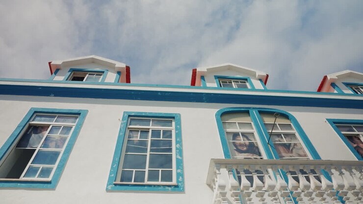 Ampia inquadratura di un vecchio edificio bianco con grandi finestre dipinte di turchese nelle Isole Azzorre, Portogallo.