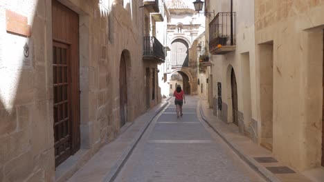 woman walking alone down narrow old street in valderrobres, teruel, spain