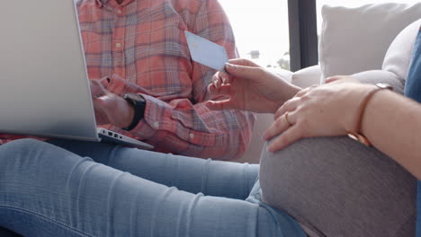 using credit card for online shopping, pregnant woman and partner with laptop