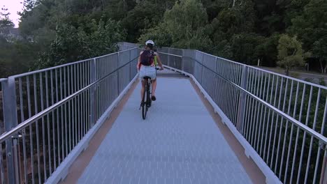 pov(point of view) shot of a man's perspective following a women on a bicycle on a steel path overlooking the ocean on magnetic island in australia.