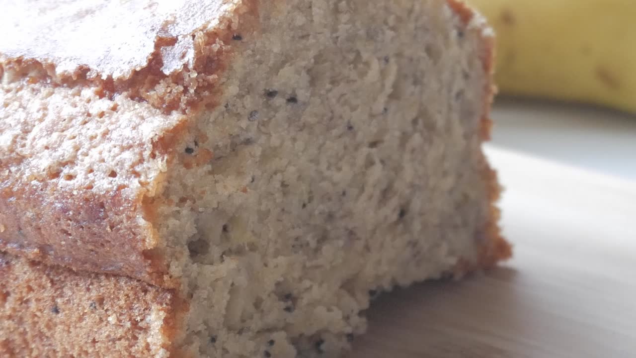 A close-up of freshly baked banana bread with a golden crust and moist texture on a wooden surface