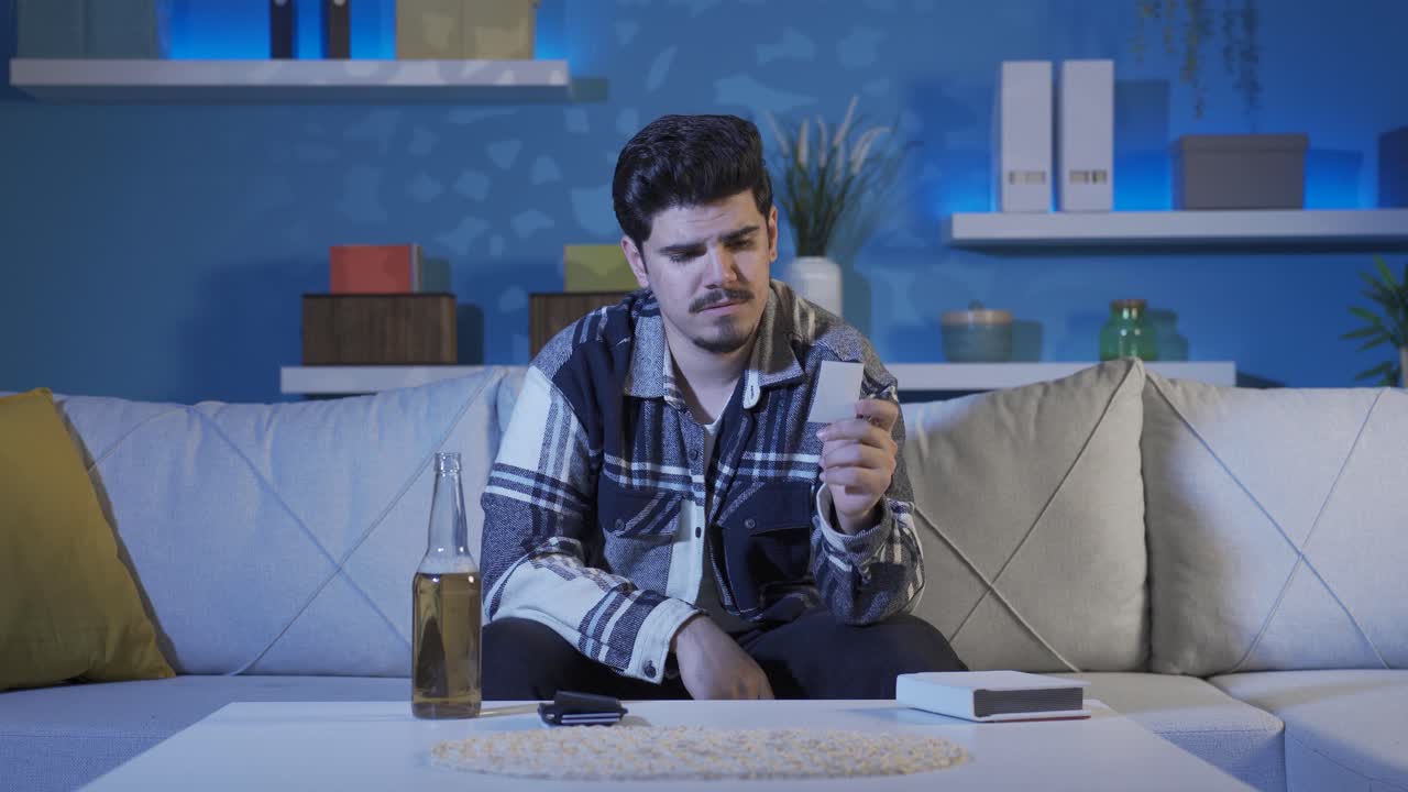 el hombre que mira la foto llora y bebe alcohol.