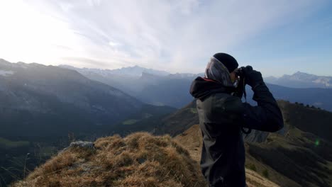 Excursionista-Mira-A-Través-De-Binoculares-Desde-La-Cima-De-Una-Montaña-Con-Mt-blanc-En-El-Fondo