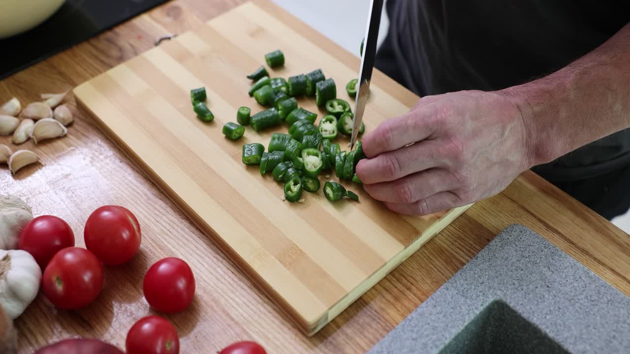 Person Chopping Green Peppers on a Wooden Cutting Board