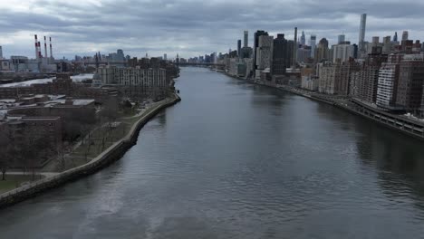 Ein-Zeitraffer-Aus-Der-Luft-über-Dem-East-River-Mit-Roosevelt-Island-Und-Manhattans-Ostseite-Im-Blick-An-Einem-Bewölkten-Tag