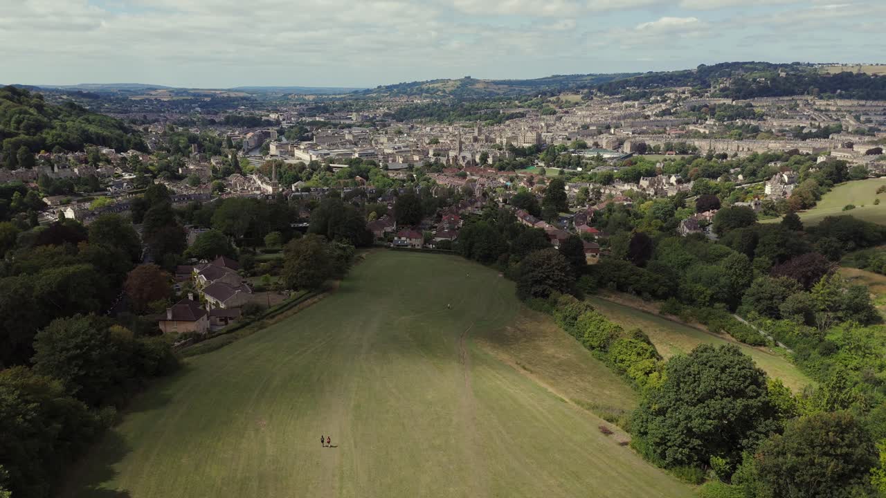 Ripresa introduttiva con drone della città di Bath in una giornata estiva, in ascesa dai campi verdi verso la città