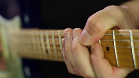 slow motion close up of an electric stratocasters guitars neck and strings and guitarists hands while playing notes with a pick. smooth slow motion with gimbal forward movement. shot in 4k at 120fps