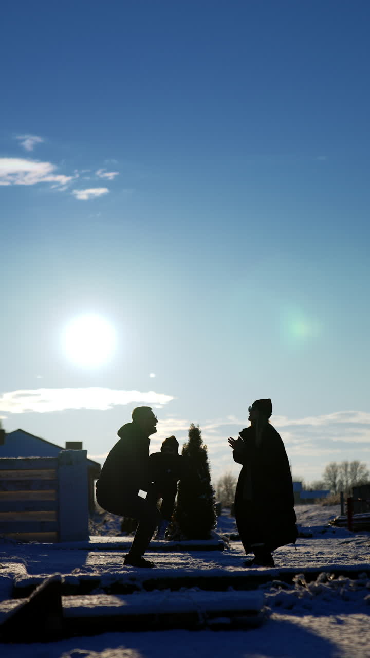 Loving parents play with their adorable baby outdoors. Man tosses his little son up high and woman claps her hands. Vertical video.