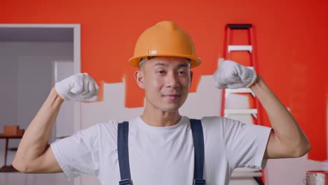 trabajador de la construcción feliz flexionando después del trabajo de pintura