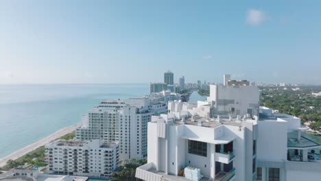 Forwards-fly-over-top-of-high-rise-apartment-building-in-modern-urban-borough-on-seaside.-Sunny-day-in-town.-Miami,-USA