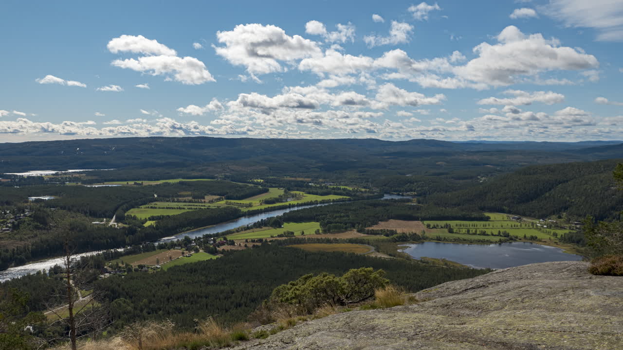 vista de lapso de tiempo de las nubes moviéndose sobre campos y bosques, en lo alto de una colina, día soleado, en el sur de noruega