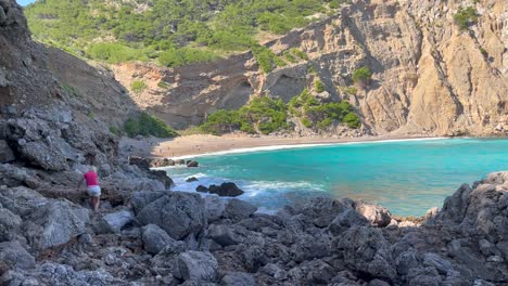 Women-Getting-Around-Rocky-Shoreside,-Coll-Baix,-Mallorca,-Spain,-Pan