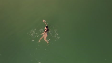 aerial directly above female in bikini swimming in beautiful green ocean surface