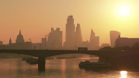 early morning sun rises behind st paul's cathedral and the city of london with waterloo bridge in foreground