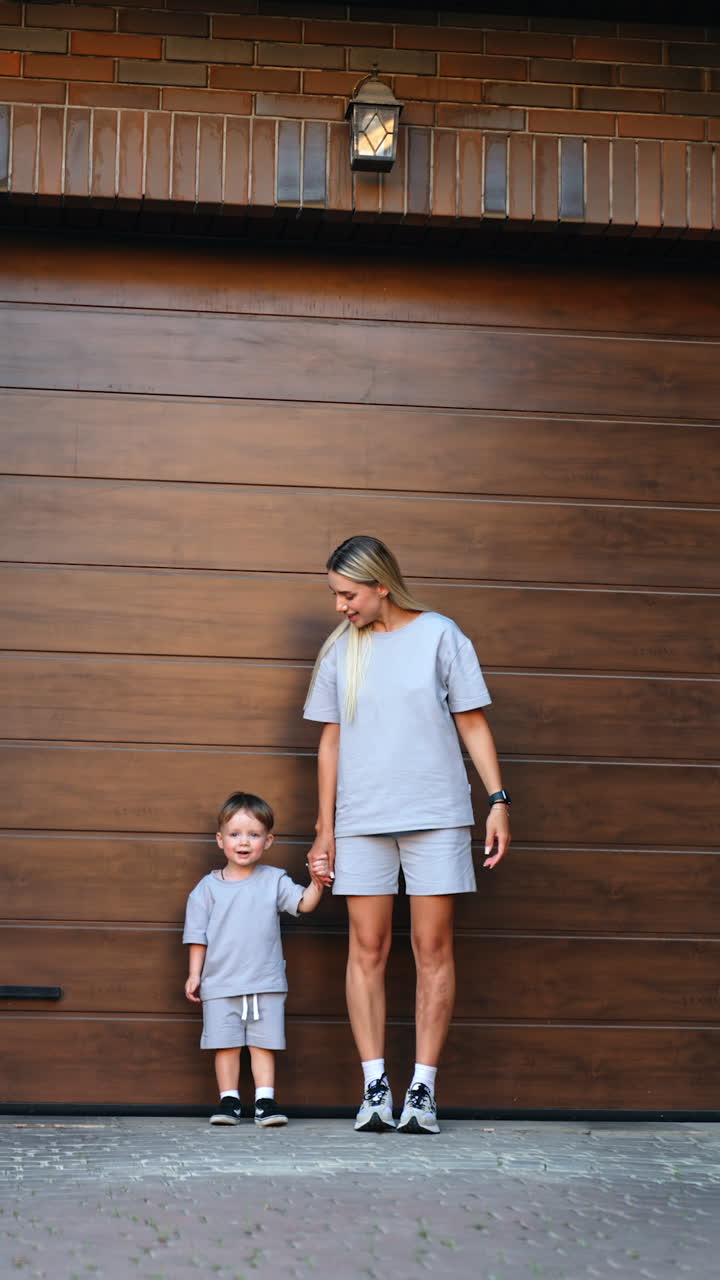 Bambino che corre, mano nella mano. Un bambino piccolo che indossa abiti grigi corre con entusiasmo tenendo la mano di un adulto in una giornata di sole.