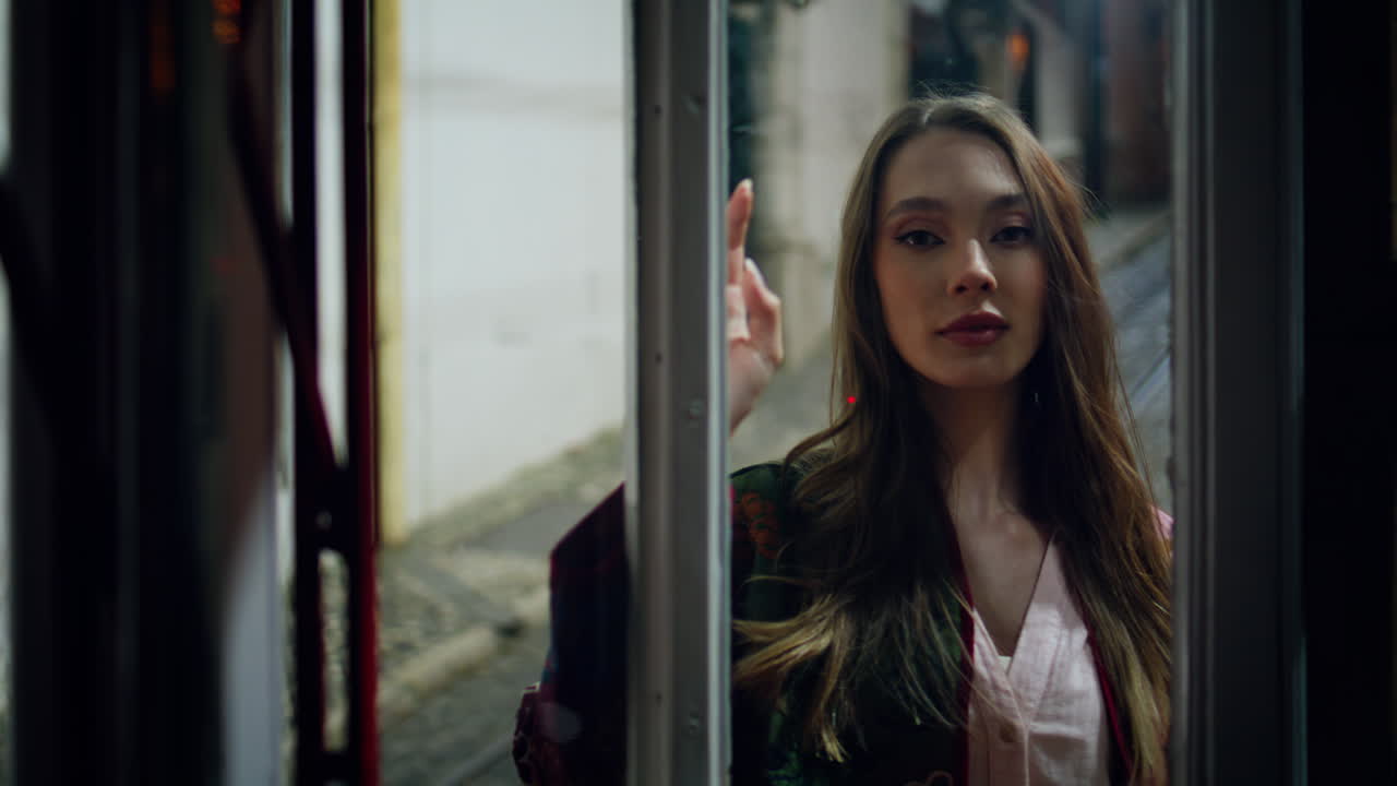 저녁 시내 거리에서 유리 문을 닫고 서 있는 감각적인 여자.