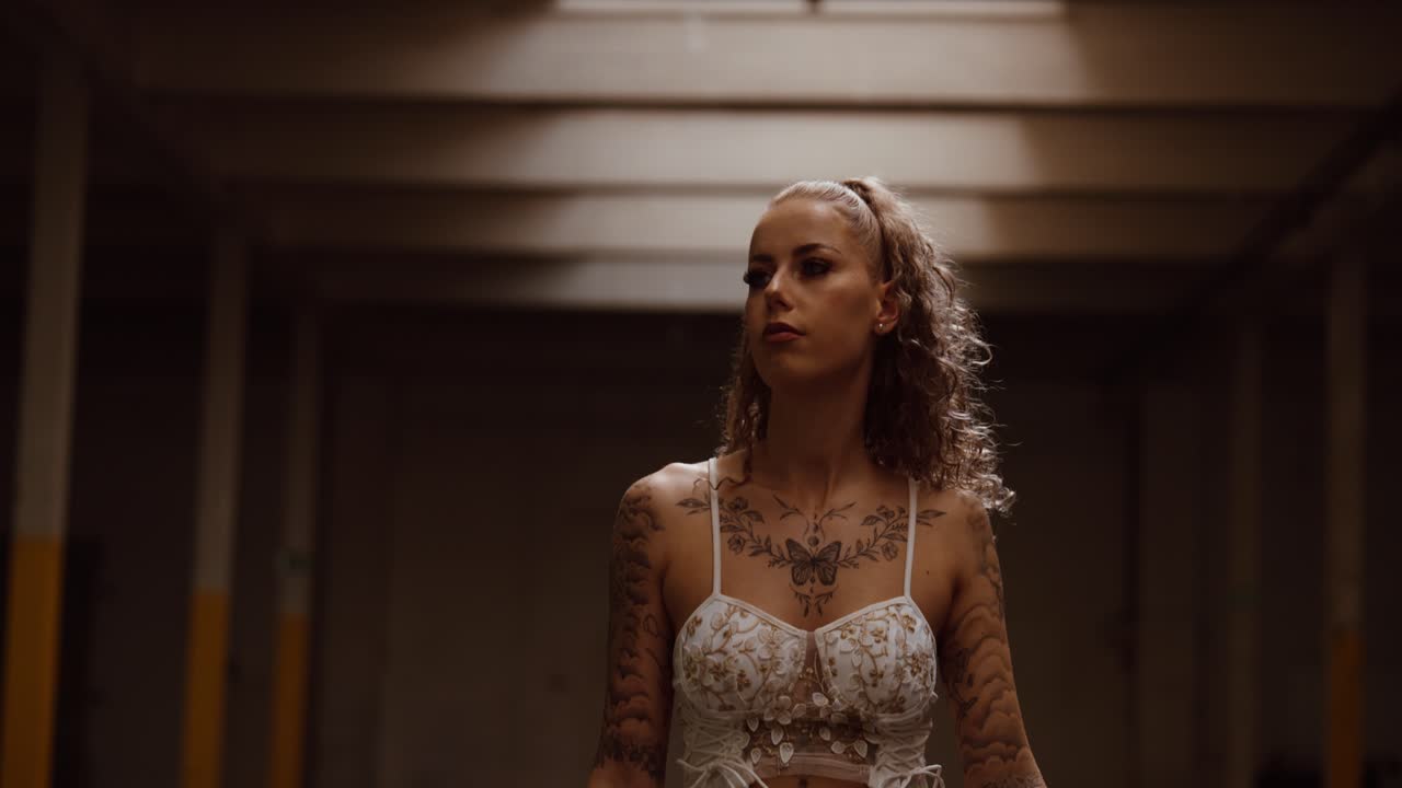 Tattooed woman posing confidently in empty industrial hall, close up, slow motion