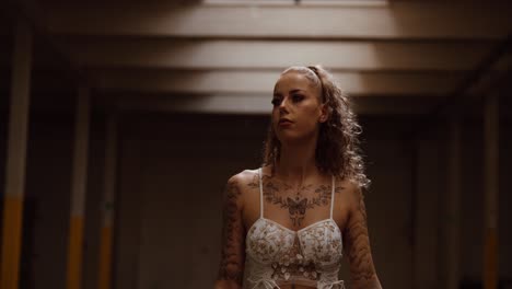 tattooed woman posing confidently in empty industrial hall, close up, slow motion