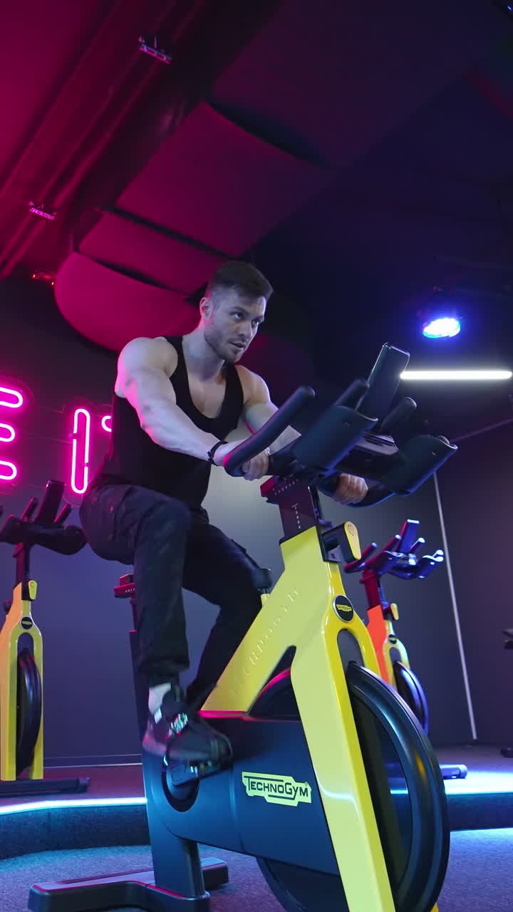 Man doing cardio workout cycling bikes. Footage of sportsman riding bike at the gym